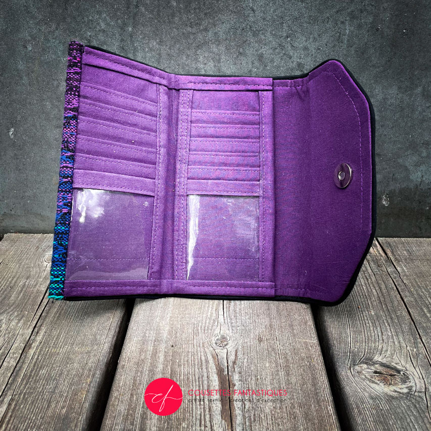 Un portefeuille fabriqué à partir d'une écharpe de portage dégradée du bleu au violet à l'extérieur et du voile violet à l'intérieur.