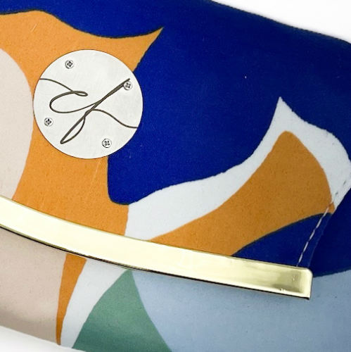 Un portefeuille pochette confectionné à partir d'une écharpe colorée avec un motif floral moderne et abstrait en blanc, bleu, sauge, beige et cannelle. À l'intérieur, on retrouve du similicuir blanc et un popeline brillant de couleur sauge claire.