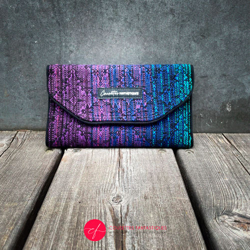 Un portefeuille fabriqué à partir d'une écharpe de portage dégradée du bleu au violet à l'extérieur et du voile violet à l'intérieur.