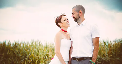 Moi et mon mari dans un champ de maïs, portant la robe de mariage de ma maman modifiée — (presque) la même robe, quelques décennies plus tard