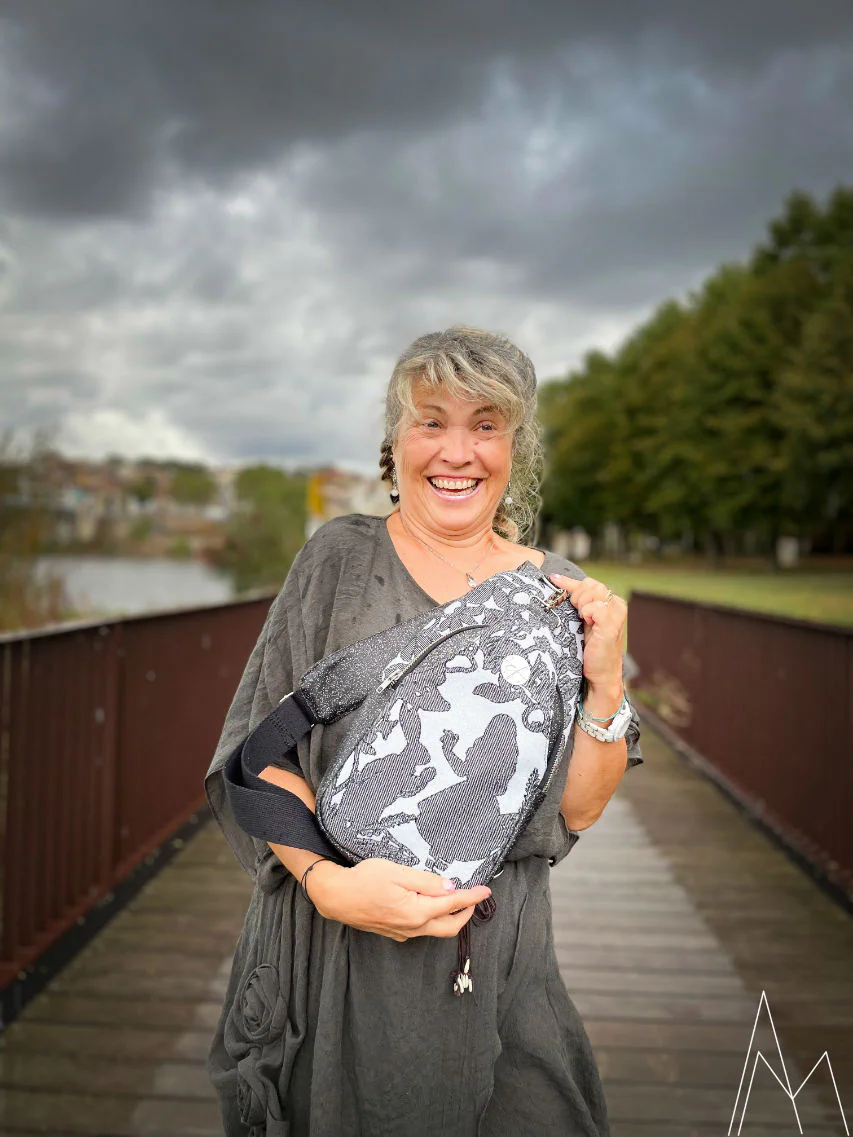 Photo d'une femme mûre portant un sac à dos gris et bleu, dans un parc en extérieur, de jour.