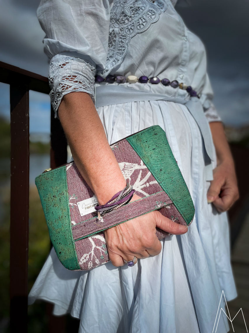 Photo of a mature white woman carrying a purse in purple and emerald green, in an outdoor park during the day.