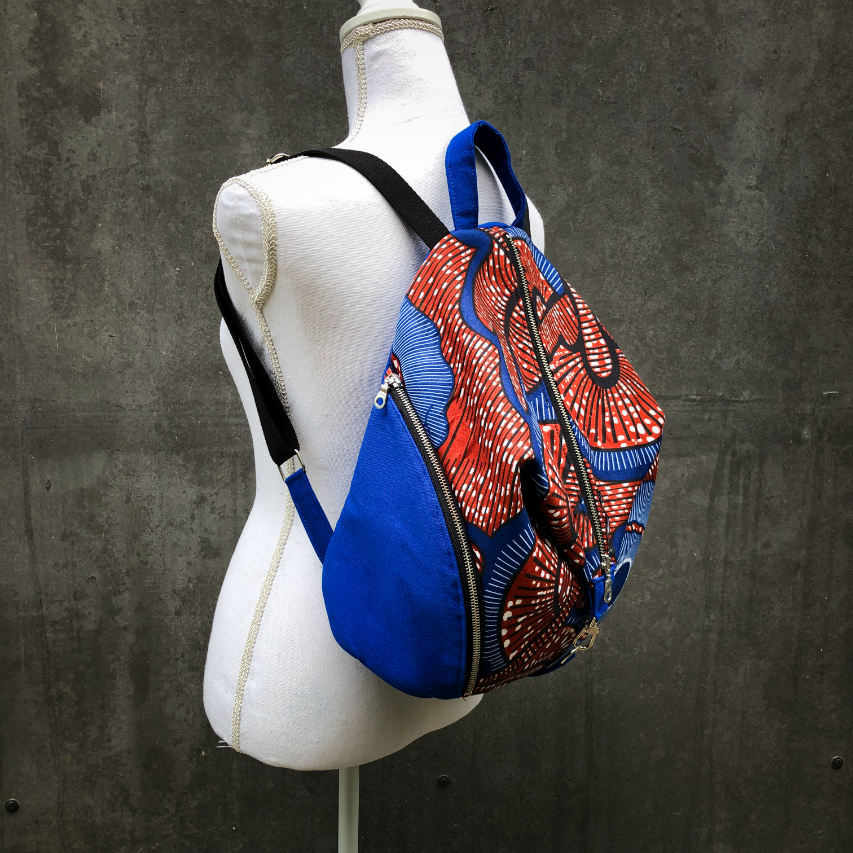 A backpack sewn with royal blue fabric and wax fabric in shades of blue, brown-red, black, and white.