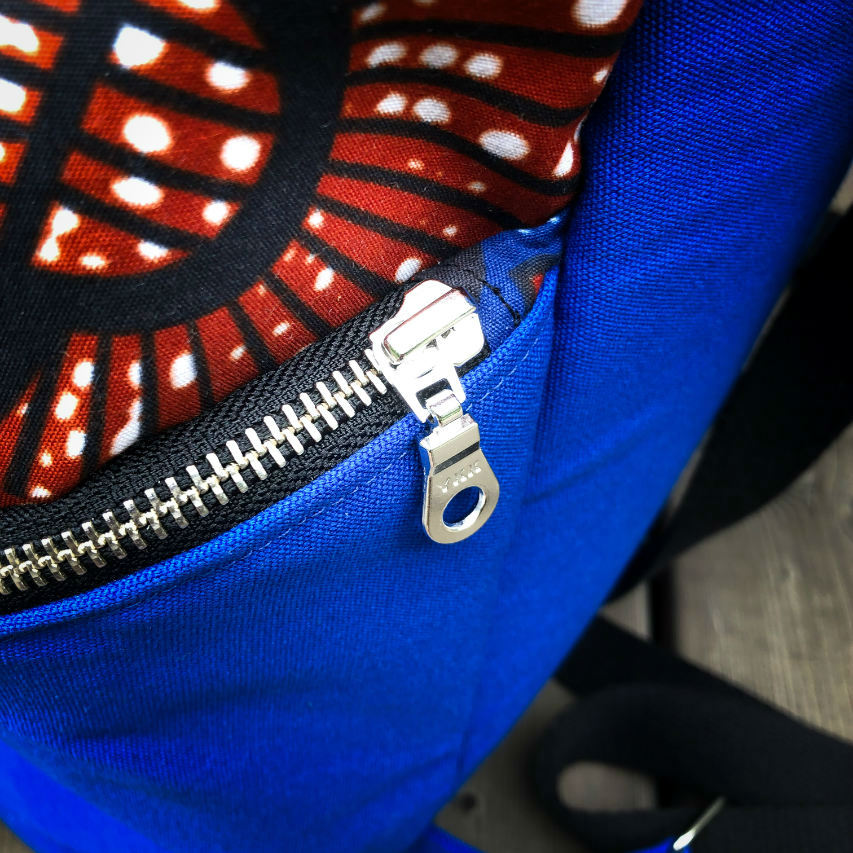 A backpack sewn with royal blue fabric and wax fabric in shades of blue, brown-red, black, and white.