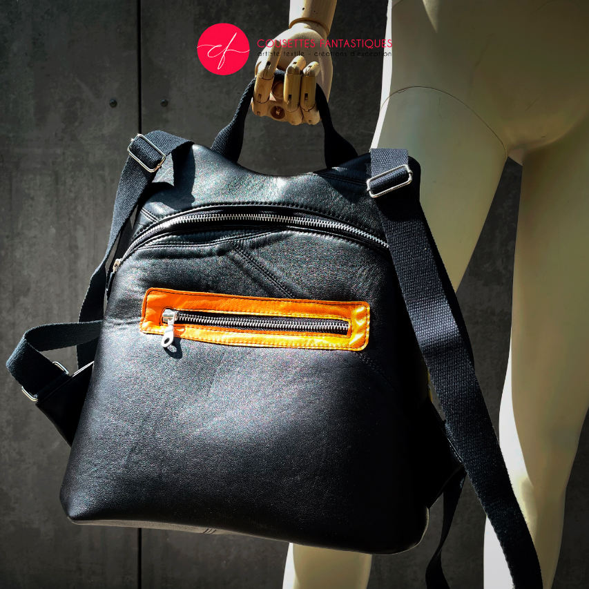 A backpack made of satin black leather, a parrot-patterned scarf, and black wool fabric.