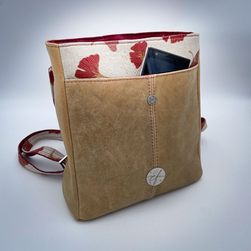A backpack made from camel colored leather and a red Ginkgo Biloba leaves patterned polycotton canvas.