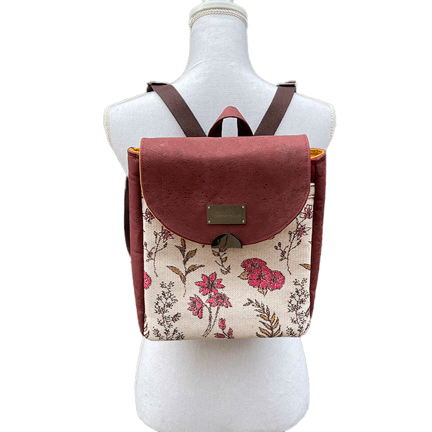 A backpack made with scarf fabric in floral patterns in pink tones on ecru background and brick cork.