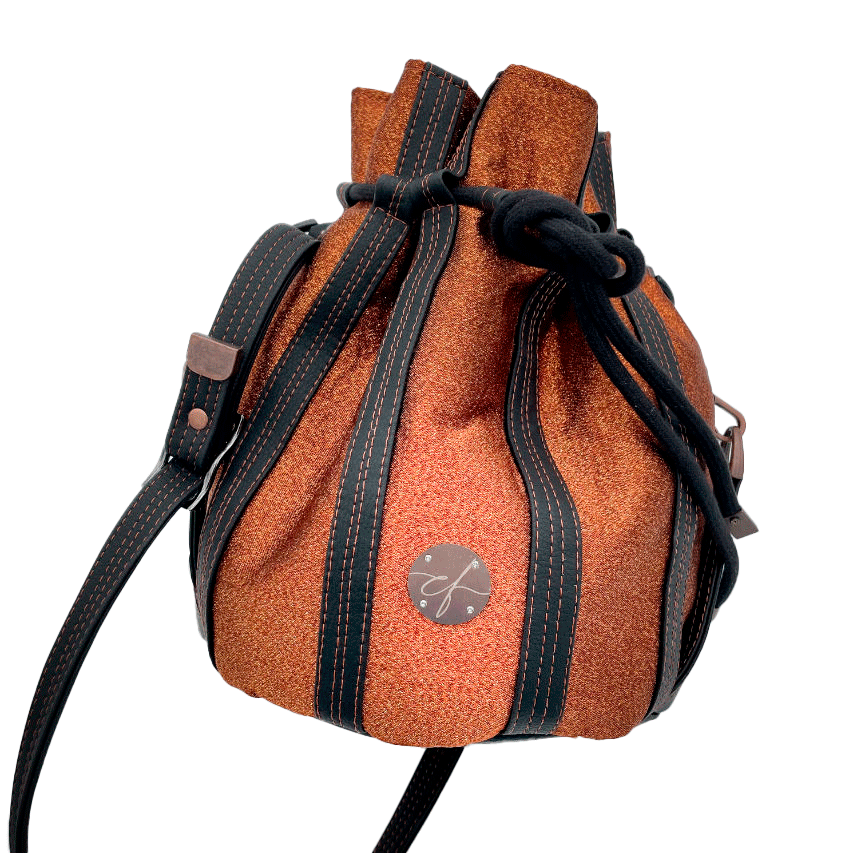 A shiny “bucket” bag made with shiny bronze fabric outlined by butter smooth matte black faux leather.