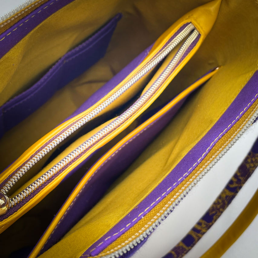 A bucket bag made from babywearing wrap fabric featuring yellow thistles on a purple background with yellow lamb leather.