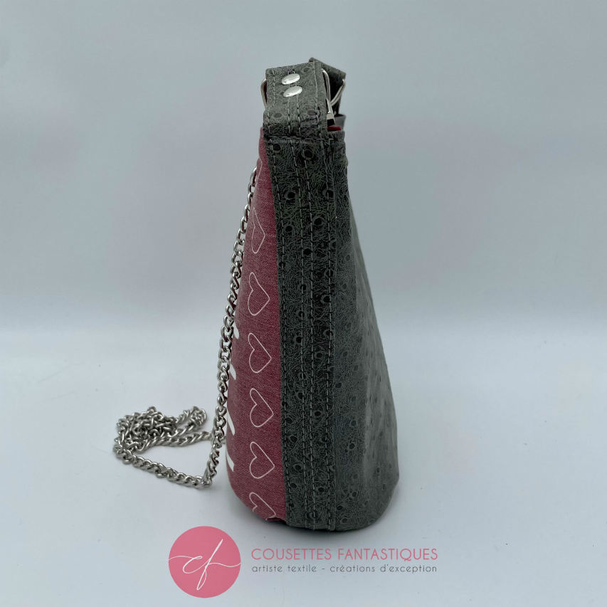 A small “bucket” bag made with delicate pink canvas featuring the word “Happy” and gray ostrich-patterned faux leather.