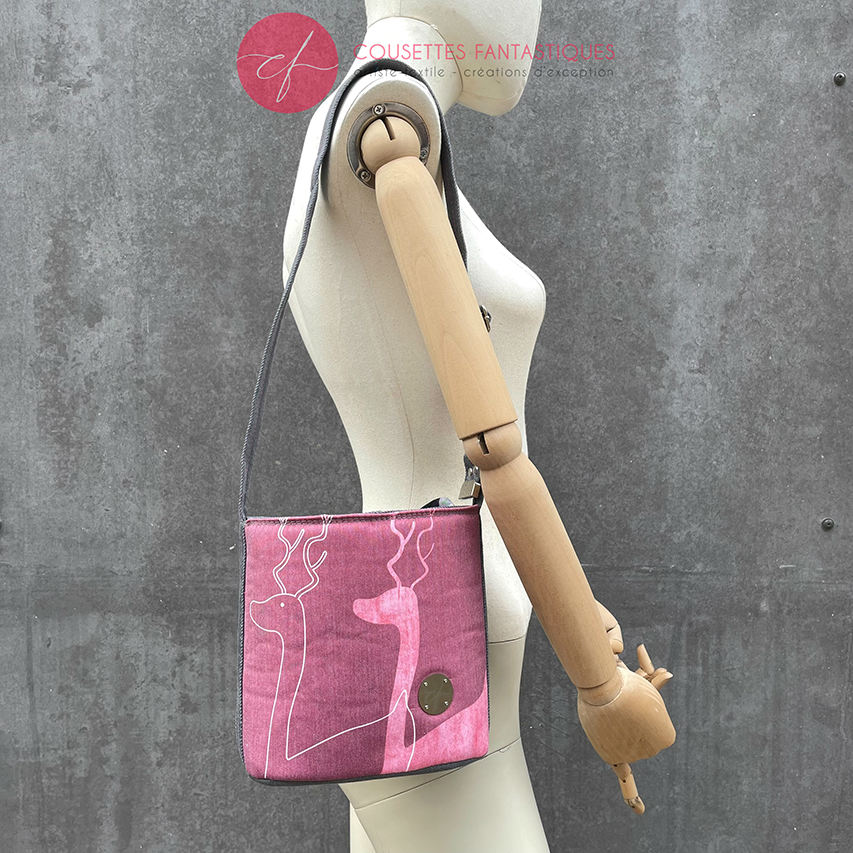 A small “bucket” bag made with delicate pink canvas featuring two white deer silhouettes and gray high-fashion denim.