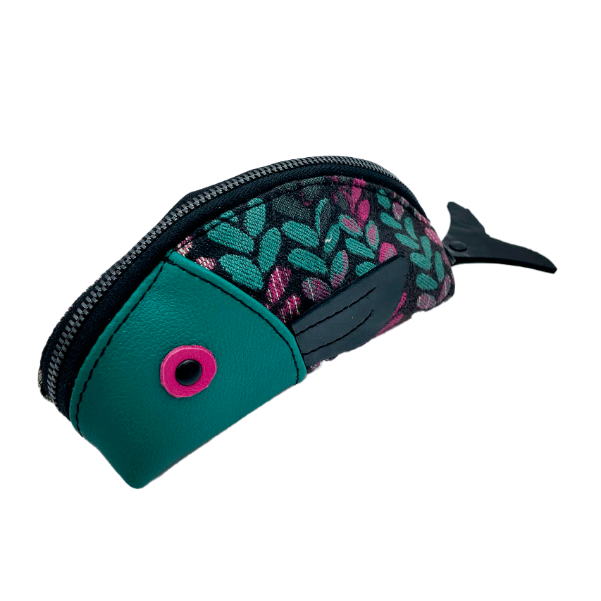 A zippered pouch sewn from sage green leather, black patent leather, fuchsia pink leather, and two scraps of a babywearing wrap with a green, beige, and pink mesh pattern on a black background.
