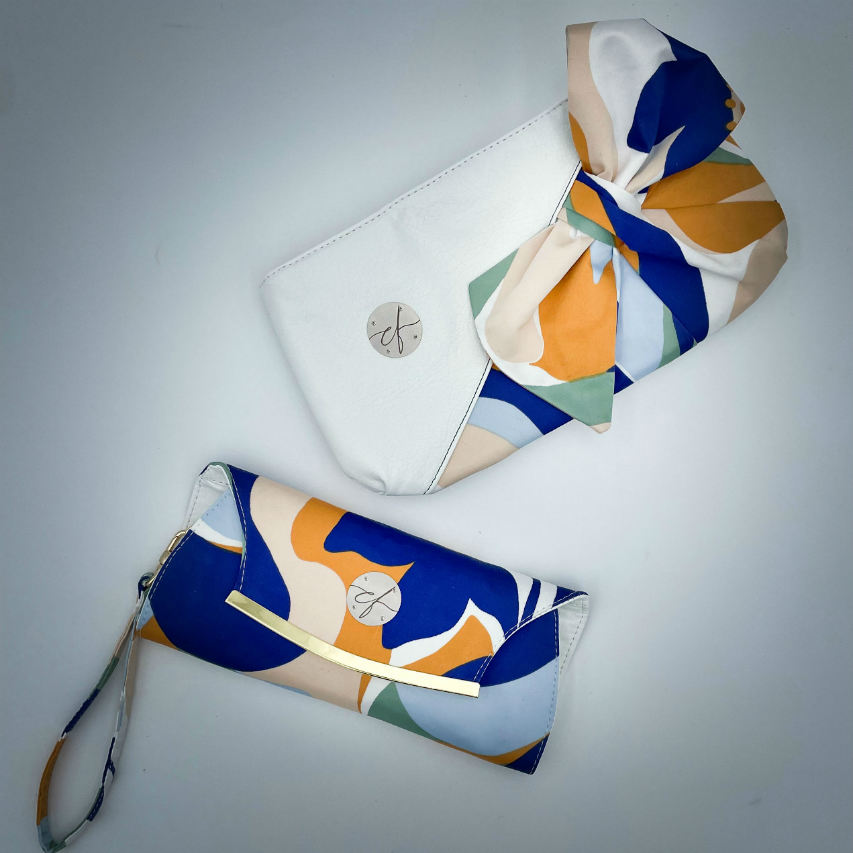 A wallet clutch made from a colorful neck scarf with an abstract and modern flowery design in white, blue, sage, beige and cinammon. Inside are white faux leather and a light sage shiny poplin.