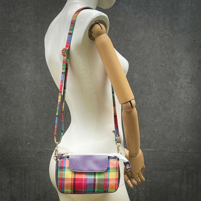 A hybrid clutch wallet bag made of purple leather and multicolored madras fabric.