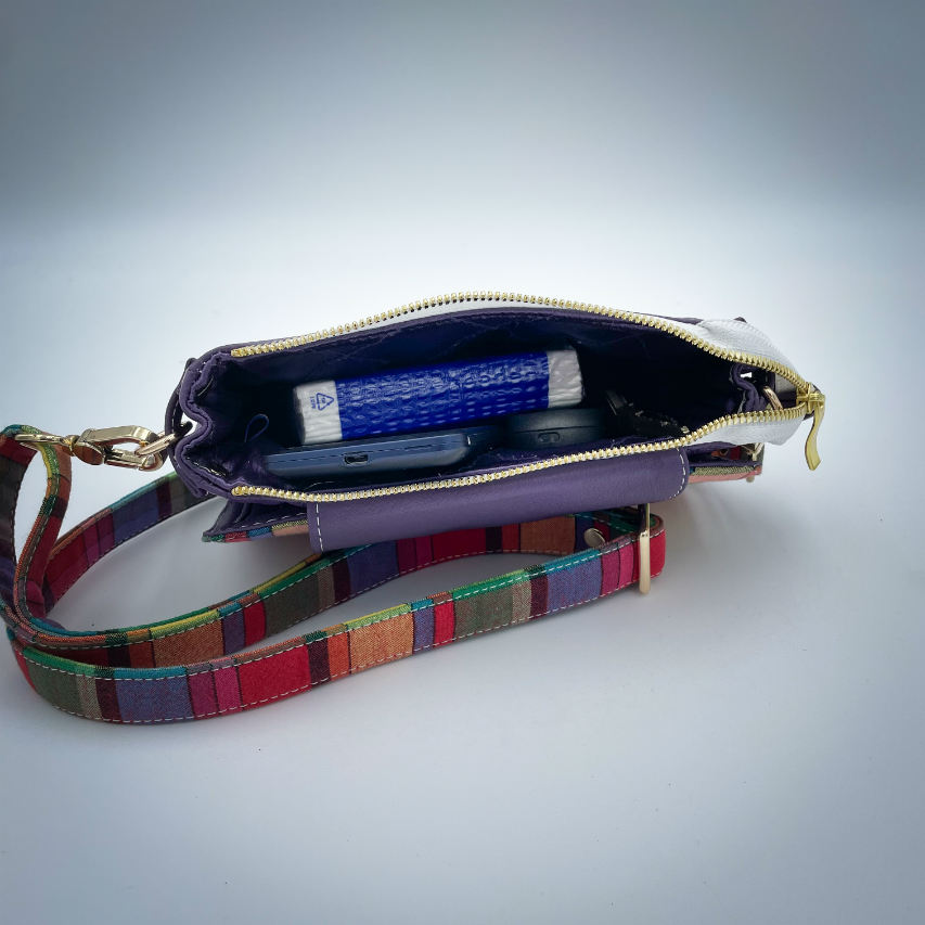 A hybrid clutch wallet bag made of purple leather and multicolored madras fabric.