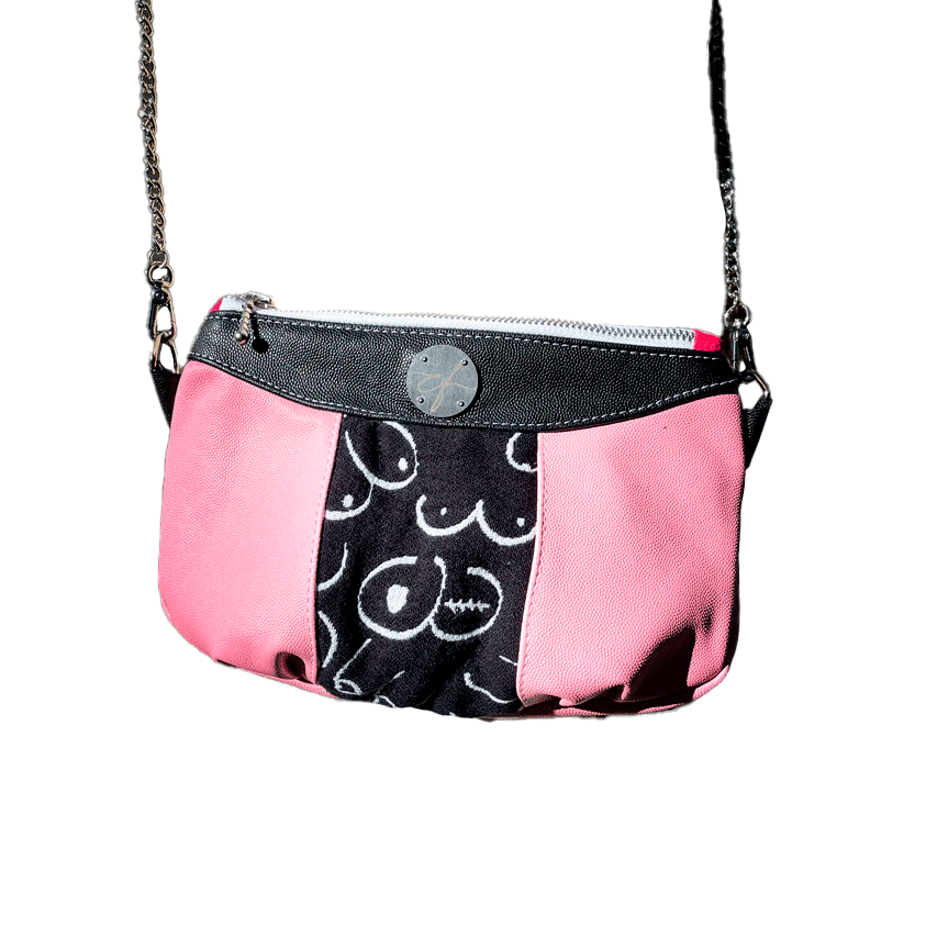 A messenger bag made from a black and white babywearing wrap with stylized breast drawings, black stingray leather, and pink stingray leather.