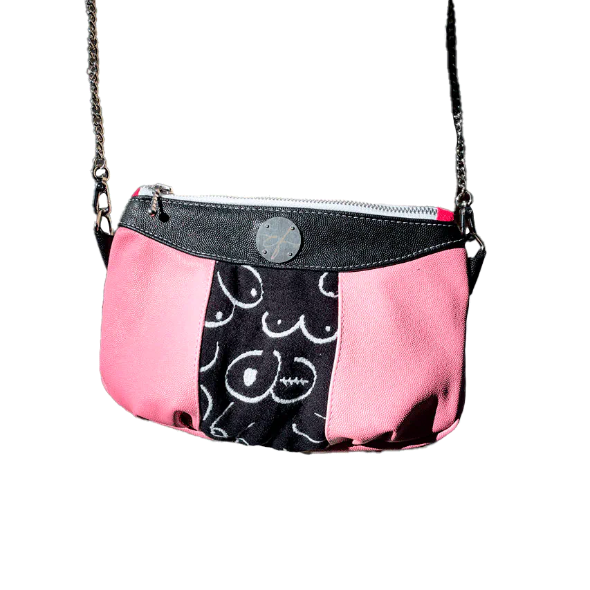 A messenger bag made from a black and white babywearing wrap with stylized breast drawings, black stingray leather, and pink stingray leather.