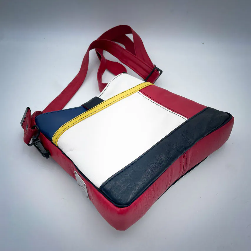 A crossbody bag made of different leathers in royal blue, deep red, bright yellow, white, and black.