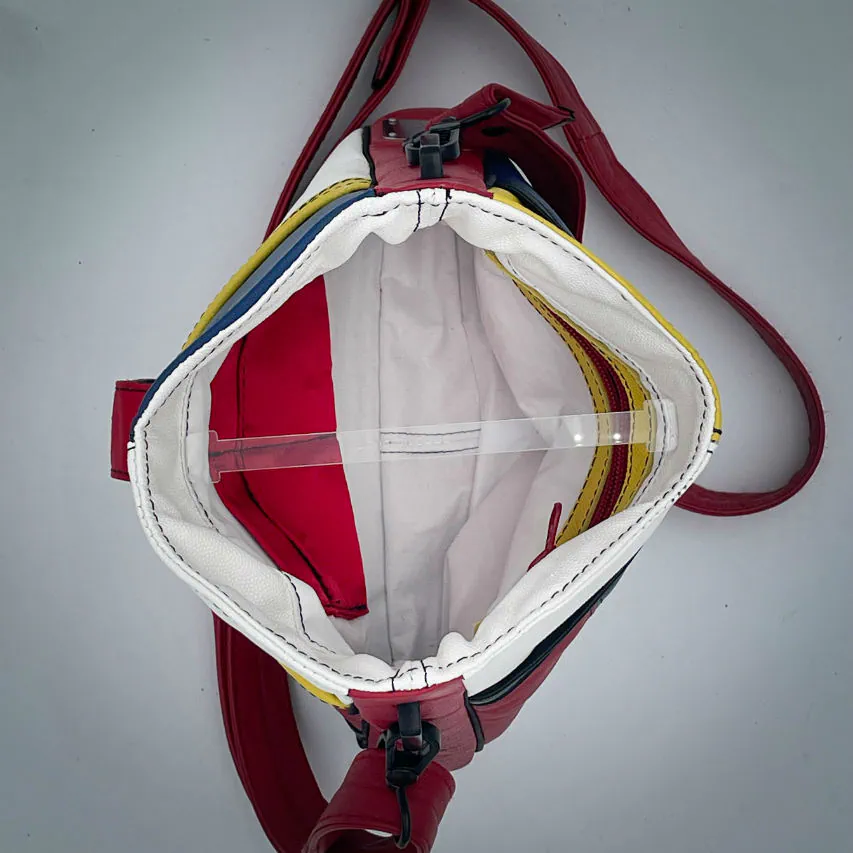 A crossbody bag made of different leathers in royal blue, deep red, bright yellow, white, and black.