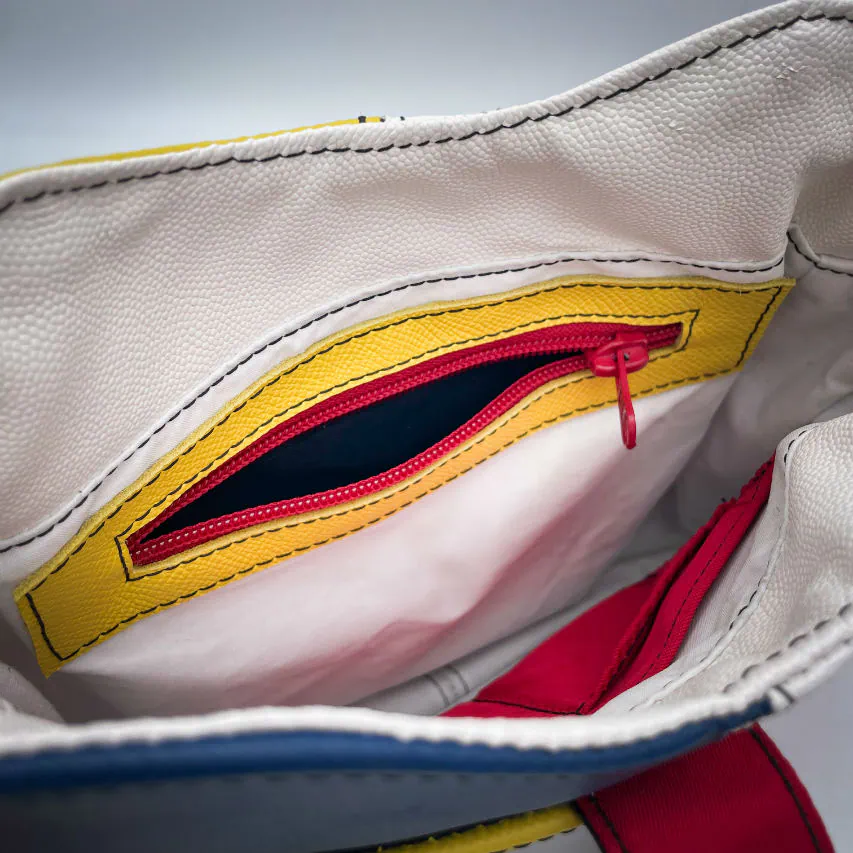 A crossbody bag made of different leathers in royal blue, deep red, bright yellow, white, and black.