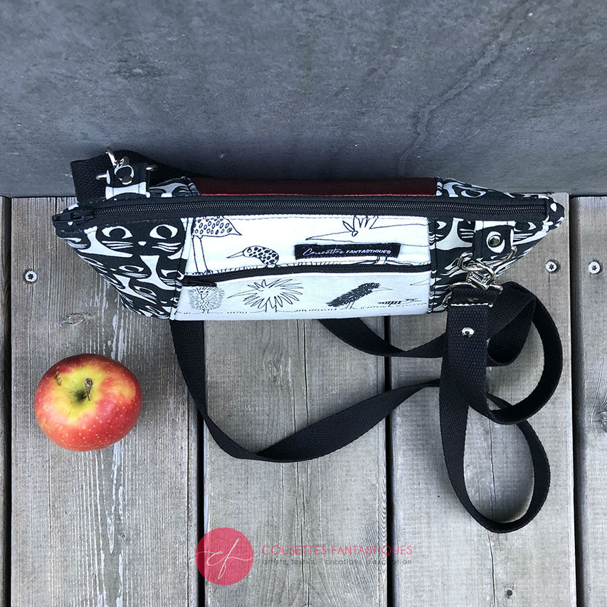 A trapezoid messenger bag made from black and white cotton fabrics on the outside with stylized cat and bird motifs, matched with bird-themed cotton cretonne on the inside.