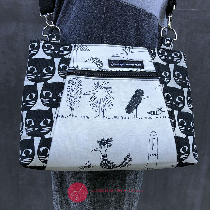 A trapezoid messenger bag made from black and white cotton fabrics on the outside with stylized cat and bird motifs, matched with bird-themed cotton cretonne on the inside.