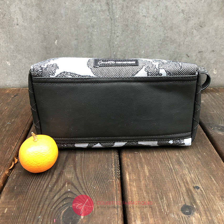 A trapezoid crossbody bag made from a black, gray-blue, and silver “Alice in Wonderland” babywearing scarf, paired with hand-quilted black faux leather.