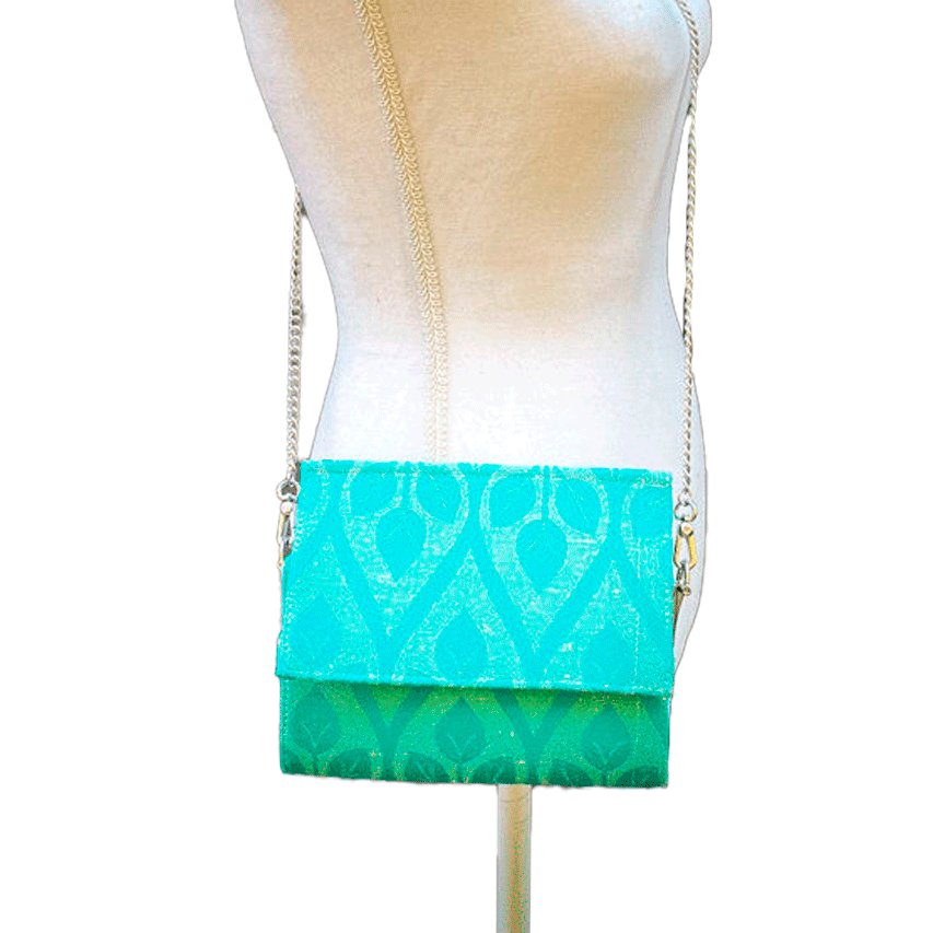 A flat handbag with a flap made from cream and turquoise babywearing wrap with stylized leaf pattern.