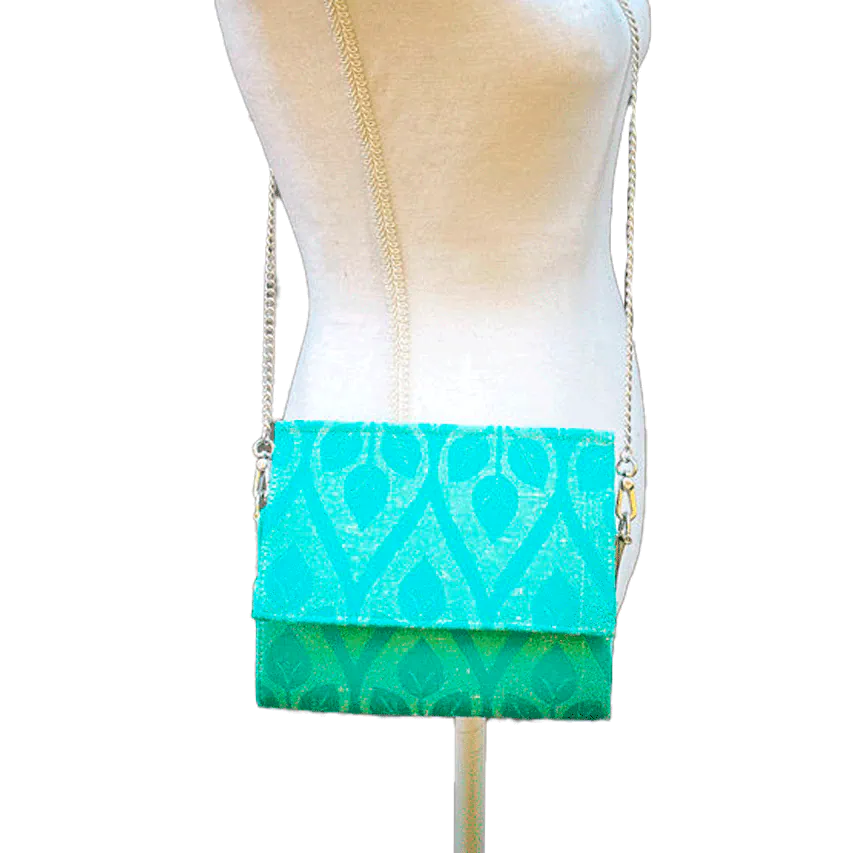 A flat handbag with a flap made from cream and turquoise babywearing wrap with stylized leaf pattern.