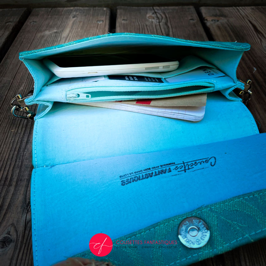 A flat handbag with a flap made from cream and turquoise babywearing wrap with stylized leaf pattern.