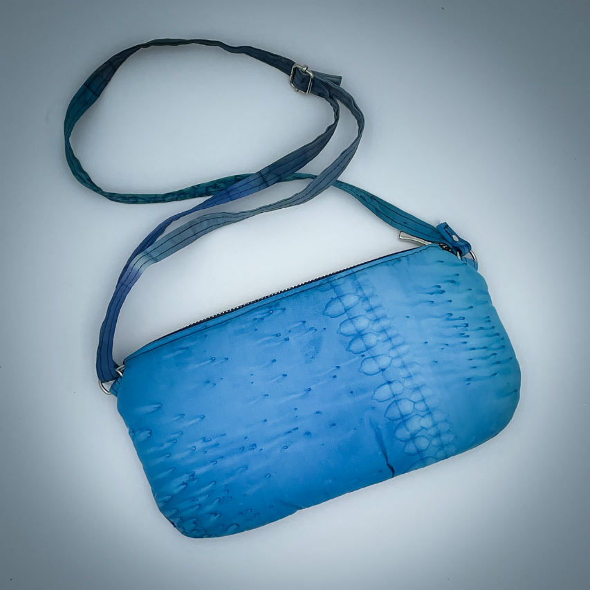 A zippered pouch sewn from a silk scarf in shades of blue, pleated and combined with royal blue cork.