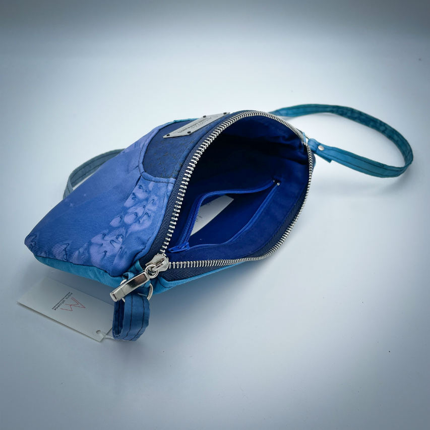 A zippered pouch sewn from a silk scarf in shades of blue, pleated and combined with royal blue cork.