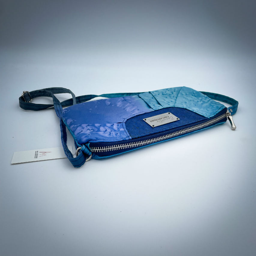 A zippered pouch sewn from a silk scarf in shades of blue, pleated and combined with royal blue cork.