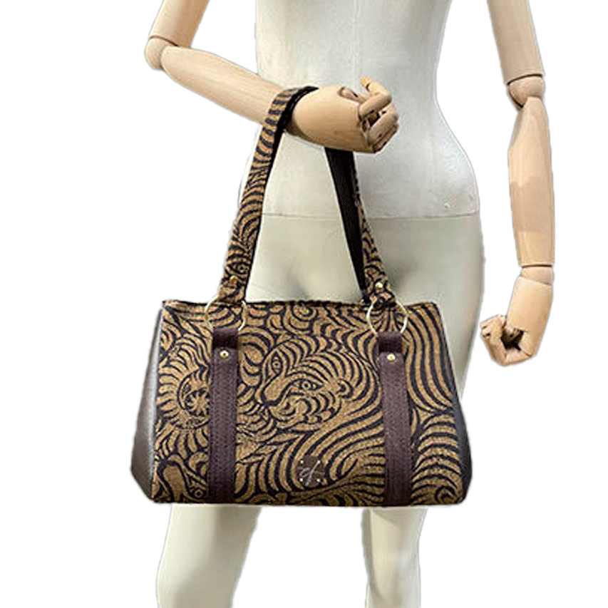 A handbag made of brown synthetic leather and brown and fawn babywearing wrap fabric with a stylized tiger pattern.