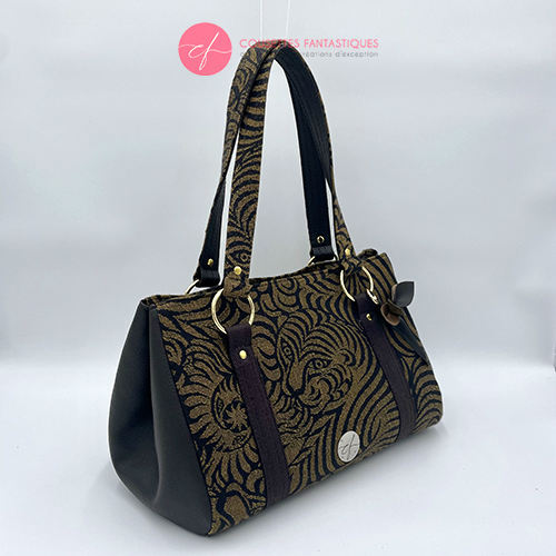 A handbag made of brown synthetic leather and brown and fawn babywearing wrap fabric with a stylized tiger pattern.