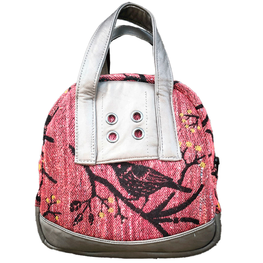 A mini handbag made of babywearing wrap scraps showing birds in a tree in pink and black tones, and grey lambskin leather.