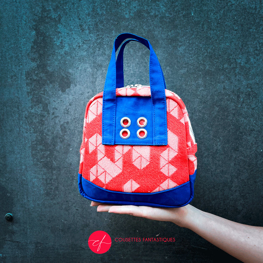 A mini handbag made of orange babywearing wrap fabric with a white geometric pattern, and blue Klein workwear fabric.