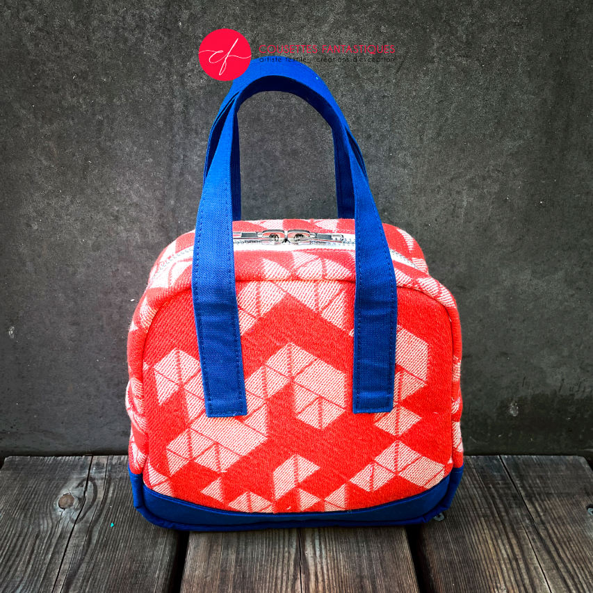 A mini handbag made of orange babywearing wrap fabric with a white geometric pattern, and blue Klein workwear fabric.