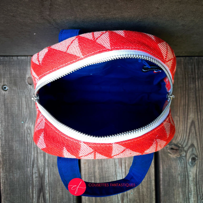 A mini handbag made of orange babywearing wrap fabric with a white geometric pattern, and blue Klein workwear fabric.