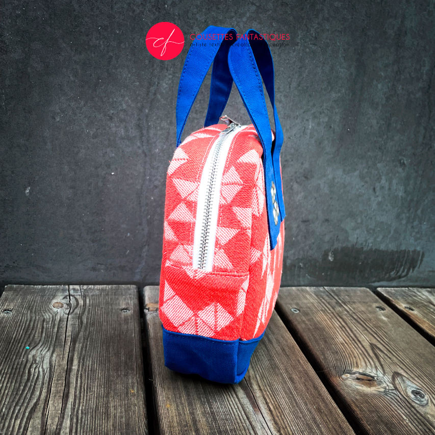 A mini handbag made of orange babywearing wrap fabric with a white geometric pattern, and blue Klein workwear fabric.