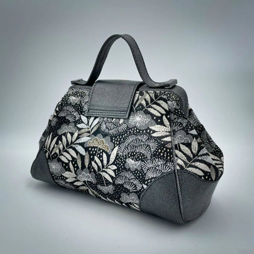 A mini handbag made of black, white, gray, and gold upholstery fabric, combined with anthracite and silver leather.