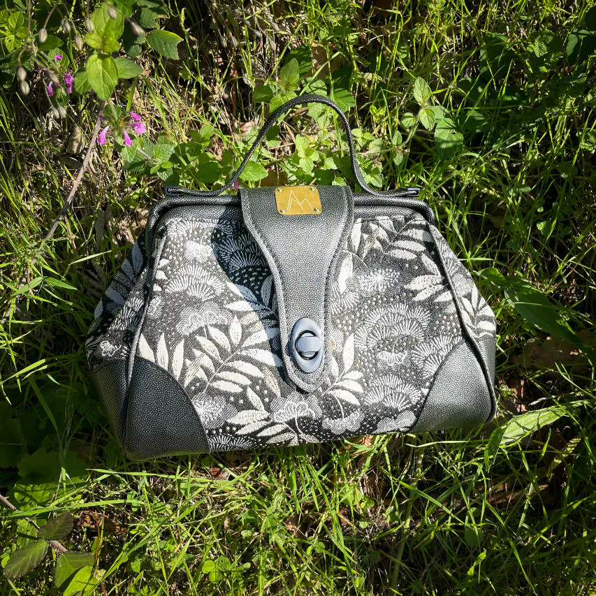 A mini handbag made of black, white, gray, and gold upholstery fabric, combined with anthracite and silver leather.