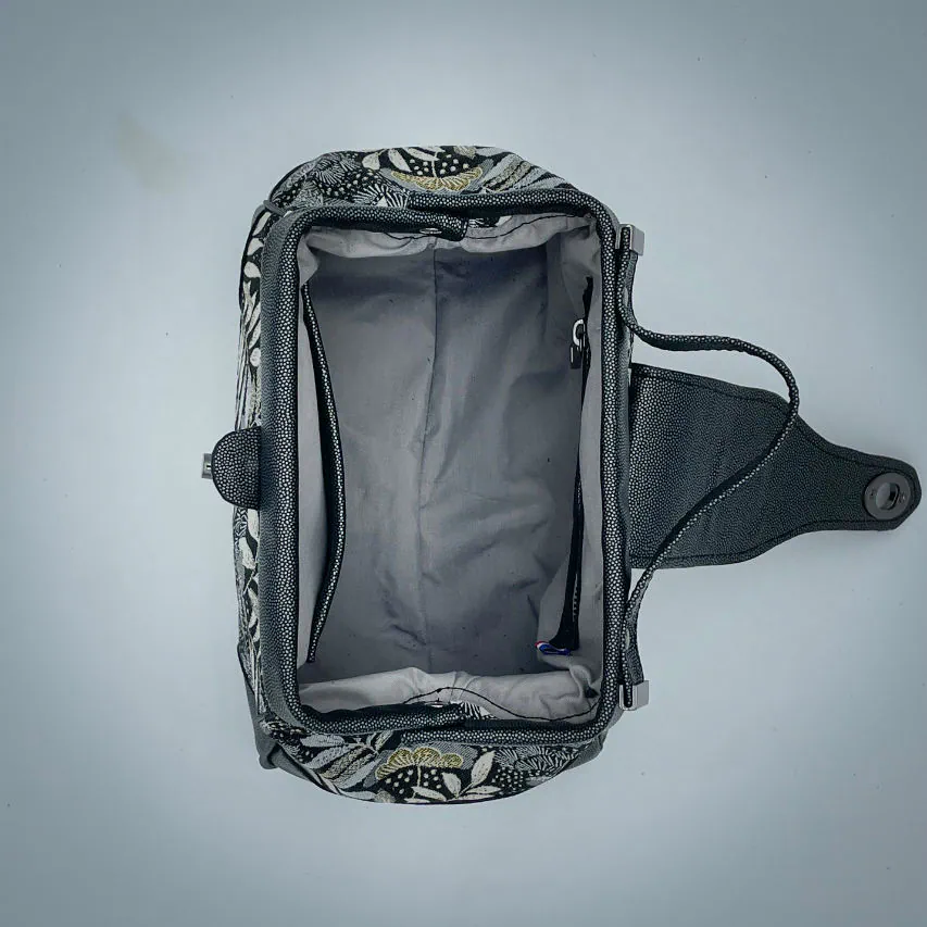 A mini handbag made of black, white, gray, and gold upholstery fabric, combined with anthracite and silver leather.