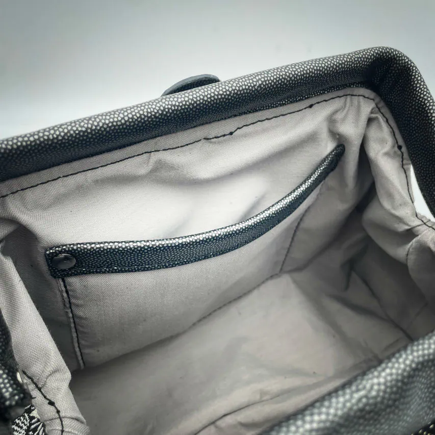 A mini handbag made of black, white, gray, and gold upholstery fabric, combined with anthracite and silver leather.