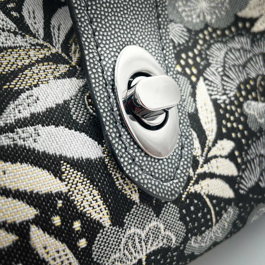 A mini handbag made of black, white, gray, and gold upholstery fabric, combined with anthracite and silver leather.