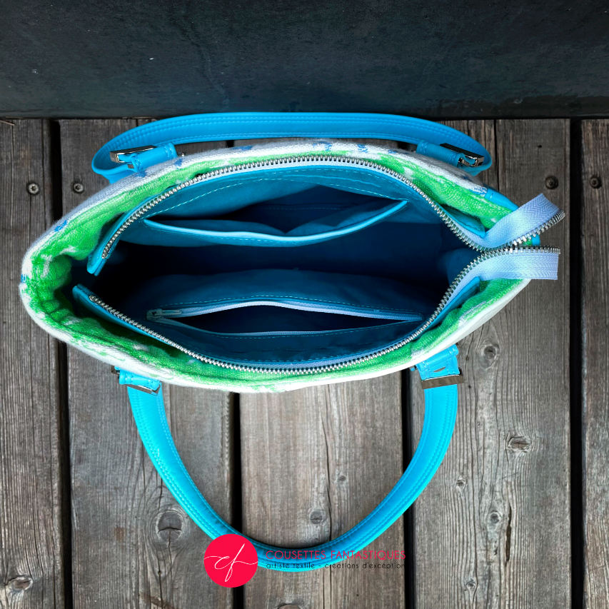 A handbag made of light blue leather and white, light blue, and apple green fabric with a bird motif.