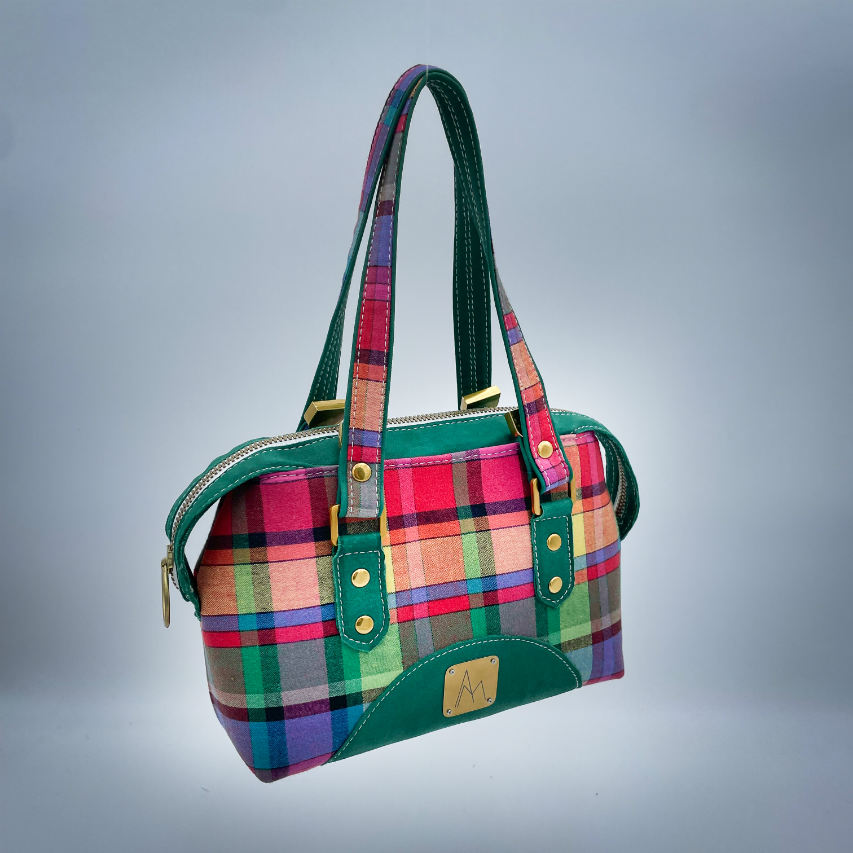 A wallet bag made of forest green leather and multicolored madras fabric.