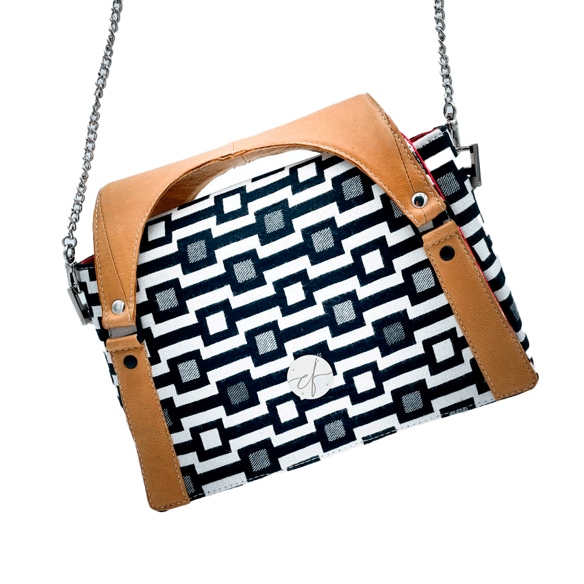 A handbag made of black and white babywearing fabric with a geometric pattern, caramel leather, and red poplin.