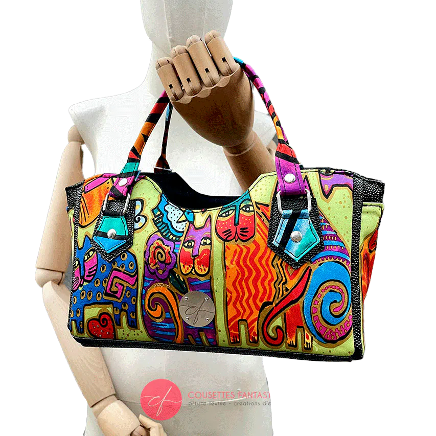 A small handbag made of shiny black faux galuchat texture and a silk scarf with a very colorful cat motif.