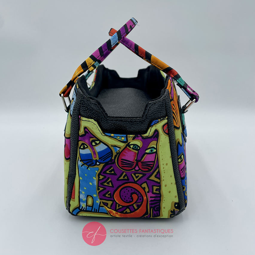 A small handbag made of shiny black faux galuchat texture and a silk scarf with a very colorful cat motif.